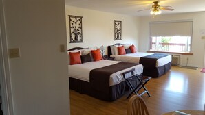 Een hotelkamer met twee bedden, een plafondventilator en een raam met uitzicht op de omgeving.
