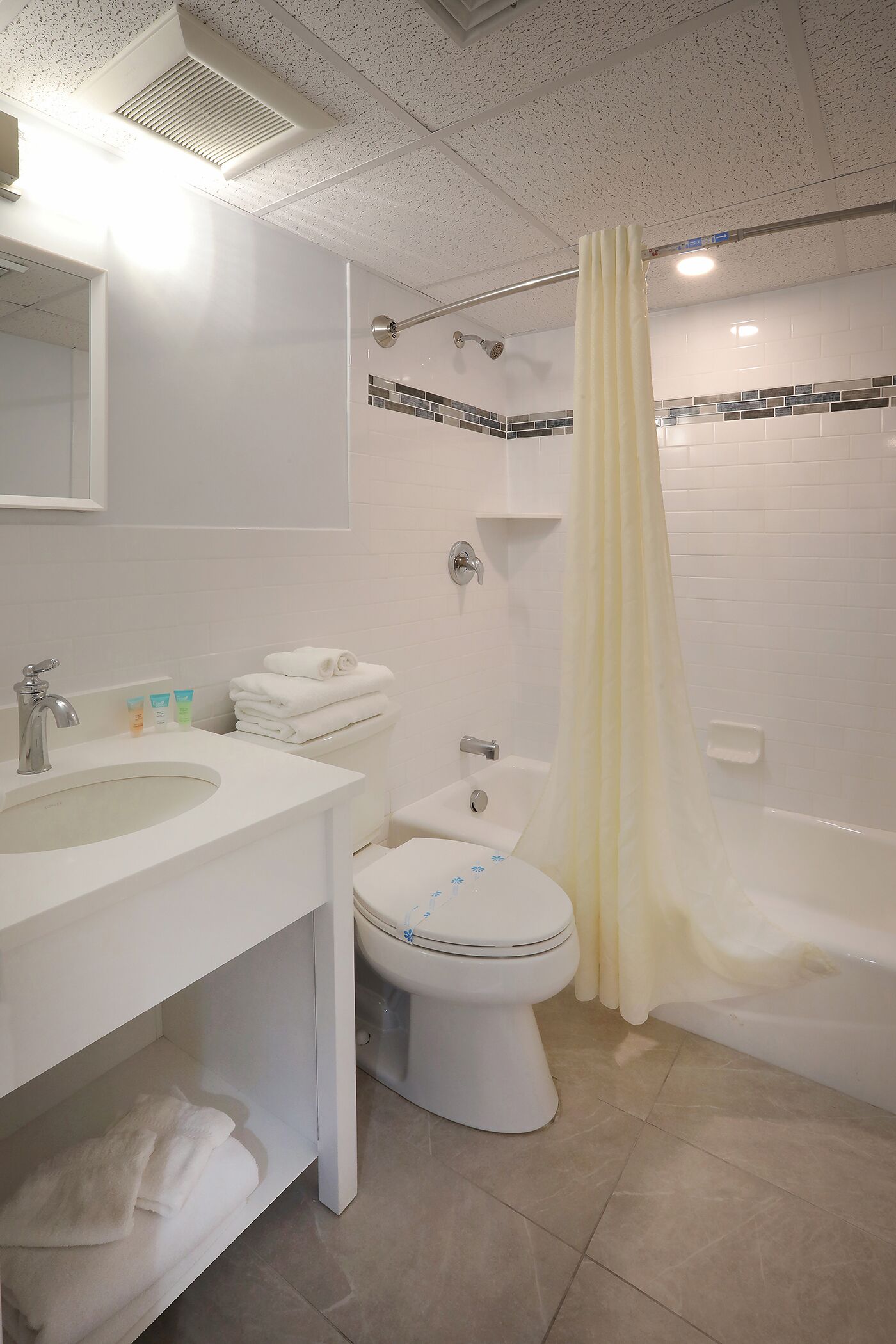 A bathroom with a sink, toilet, and bathtub, featuring white fixtures and a tiled backsplash.