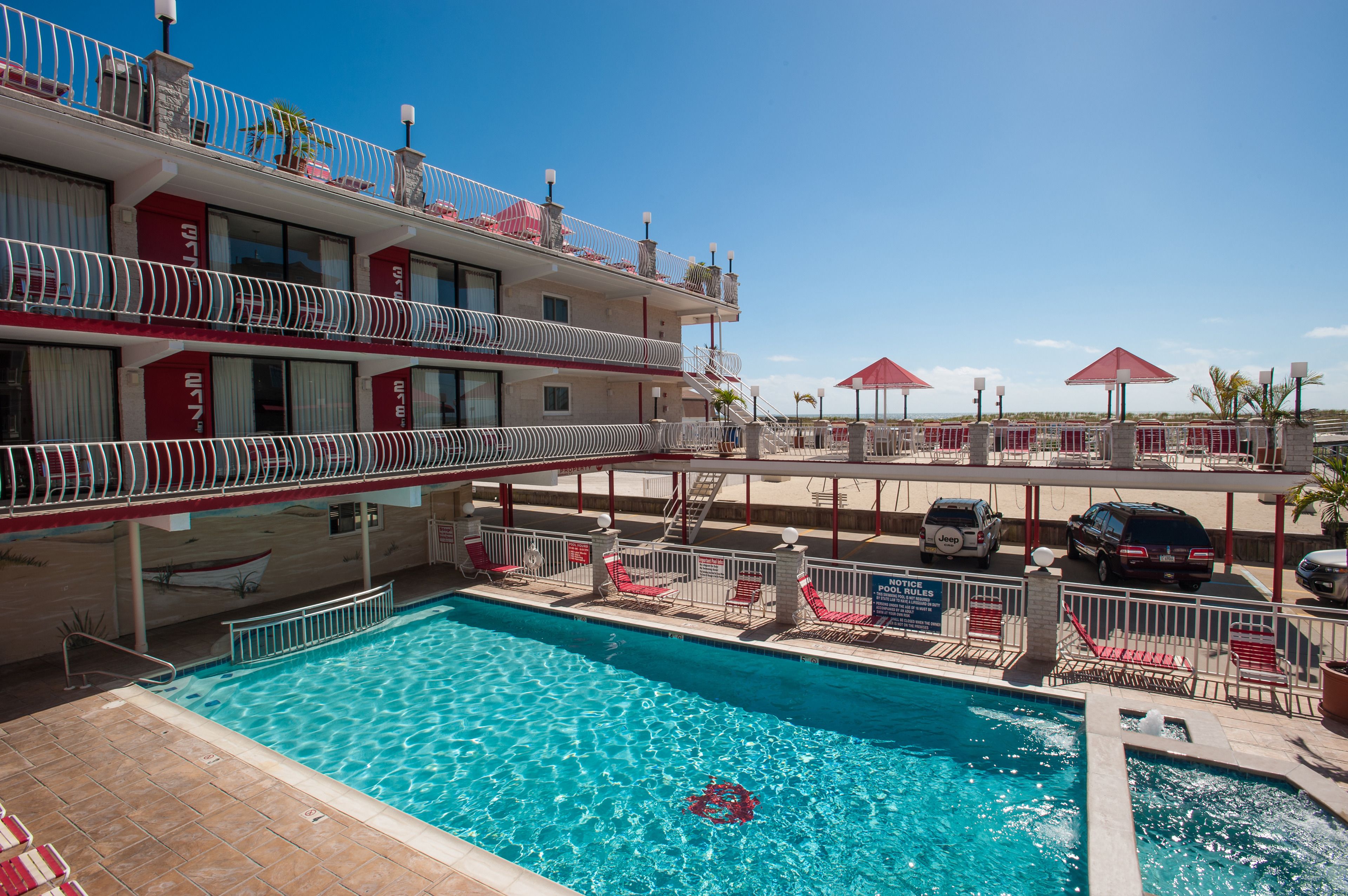 A hotel with a swimming pool, multiple balconies, and outdoor seating areas.