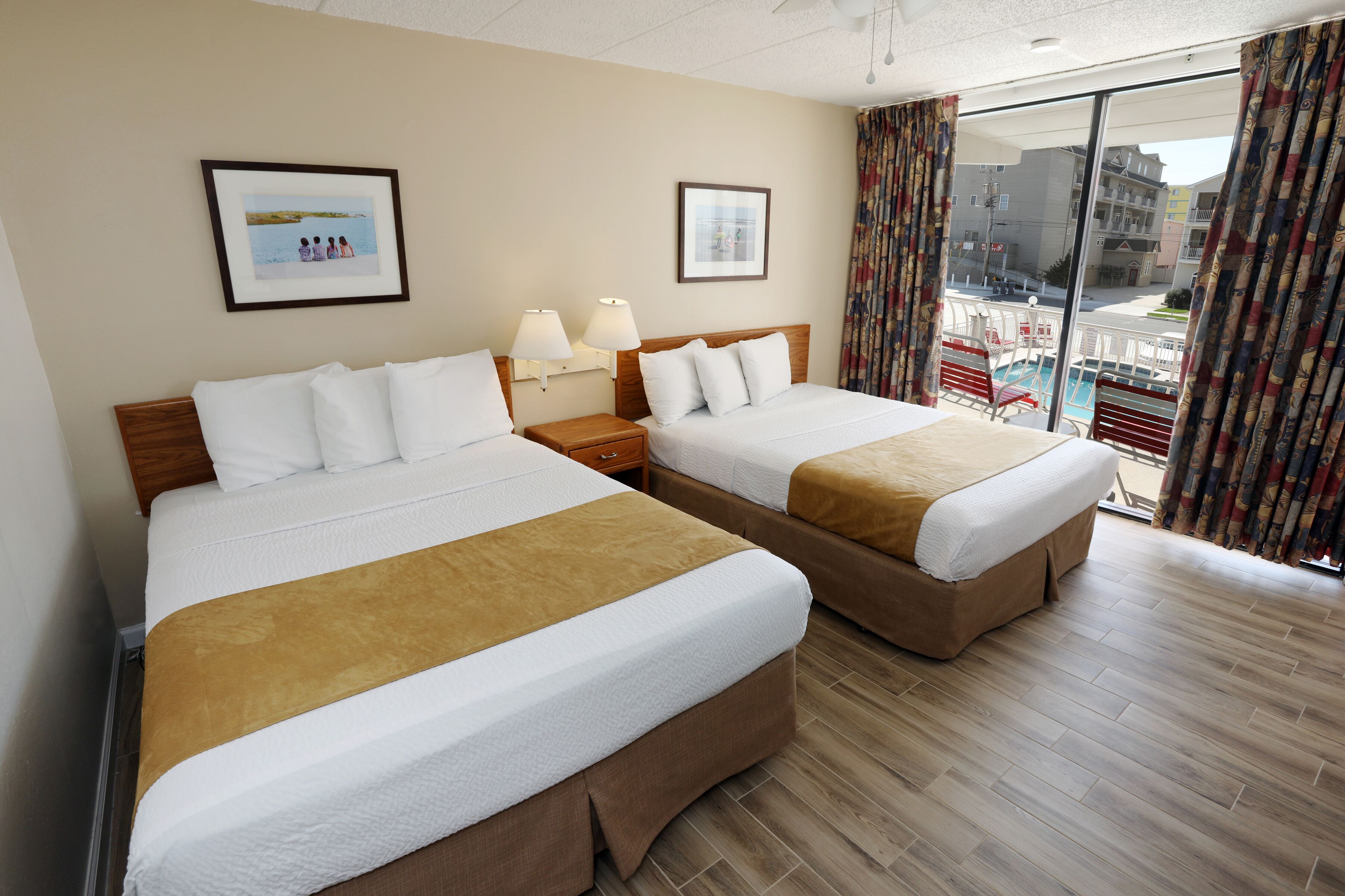 A hotel room with two beds, a large window with curtains, and a view of the outside.