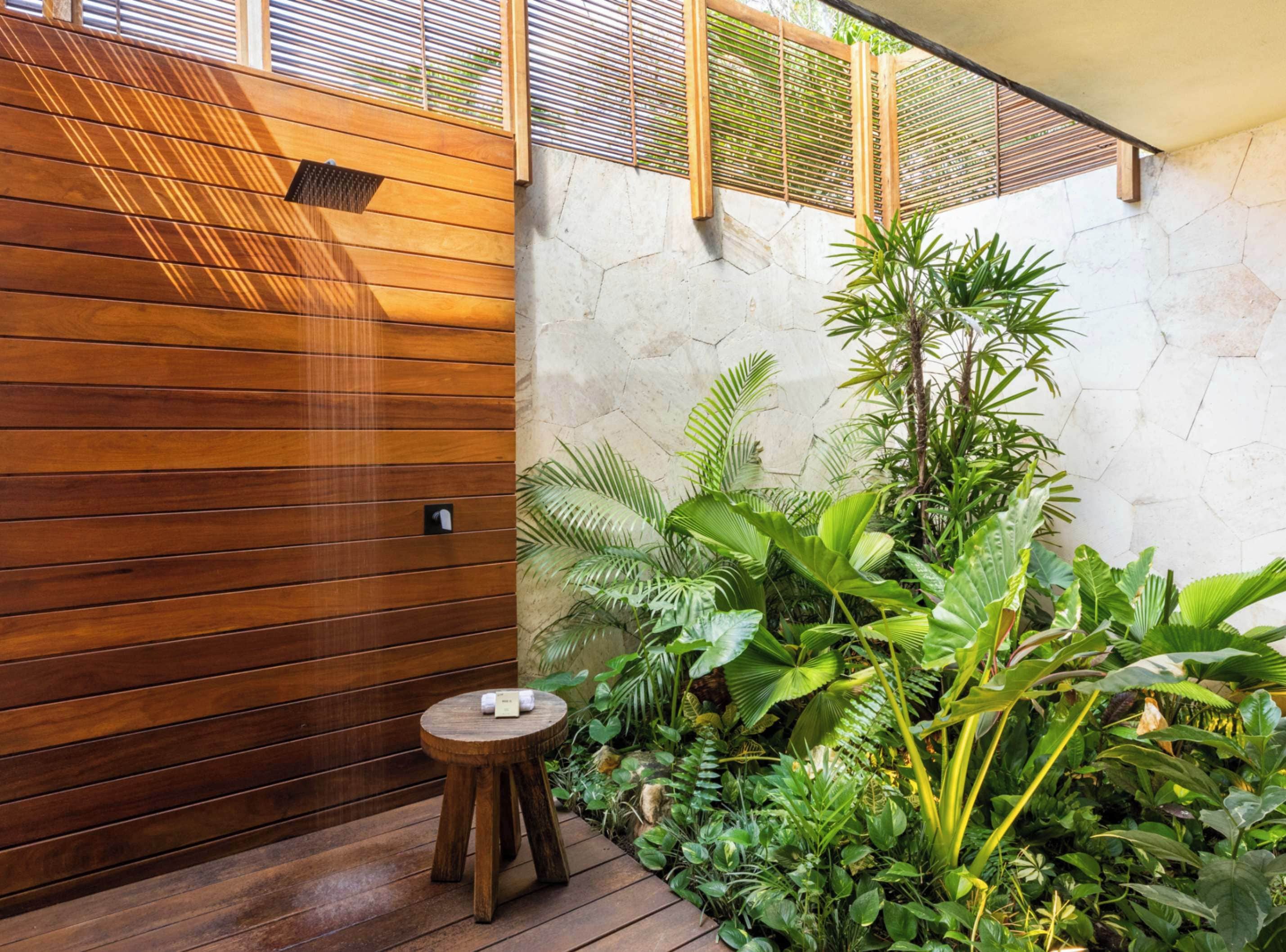Una pared de madera con un taburete pequeño y plantas verdes exuberantes.