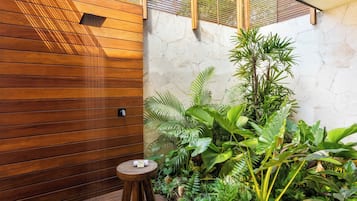Una pared de madera con un taburete pequeño y plantas verdes exuberantes.