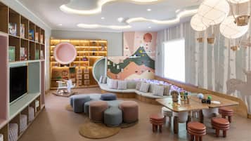 Children can play and learn in this cozy space with a cushioned bench, TV, and bookshelf filled with toys and books.