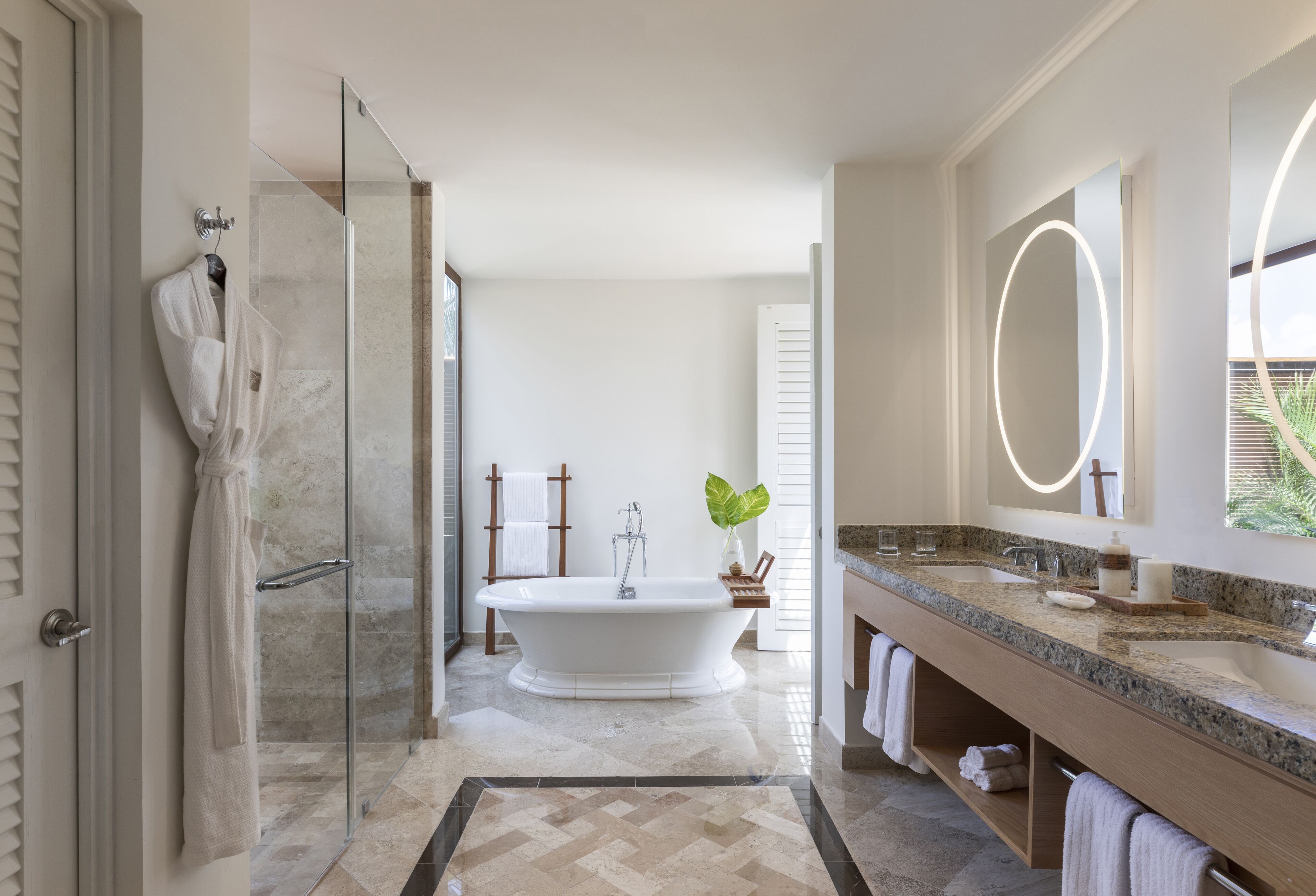 Un baño moderno con una bañera independiente, un espejo grande y una encimera de granito.