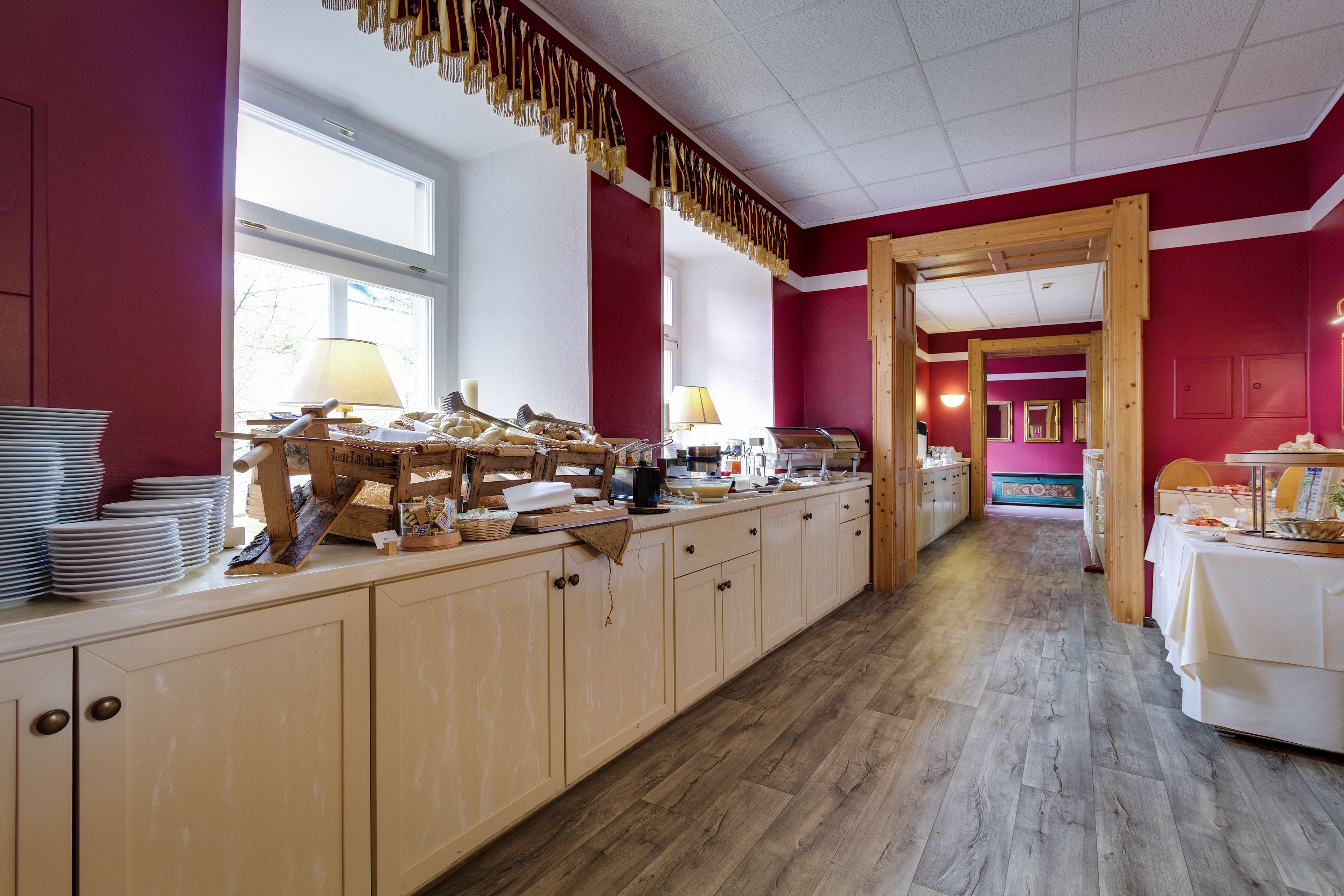 A kitchen with wooden cabinets, a long counter, and a view of a dining area.