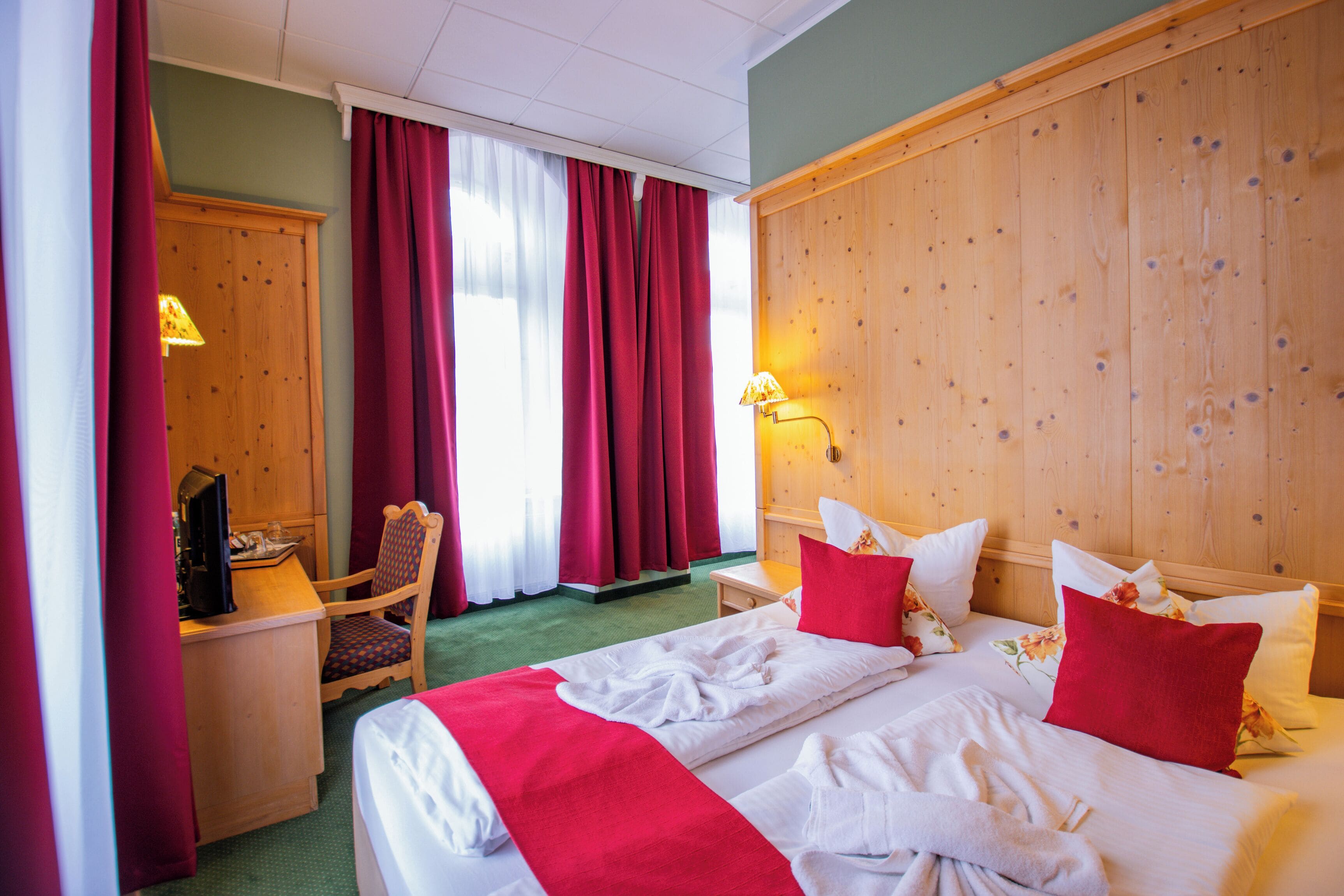 Een hotelkamer met een bed, een bureau, een stoel en een houten hoofdeinde.