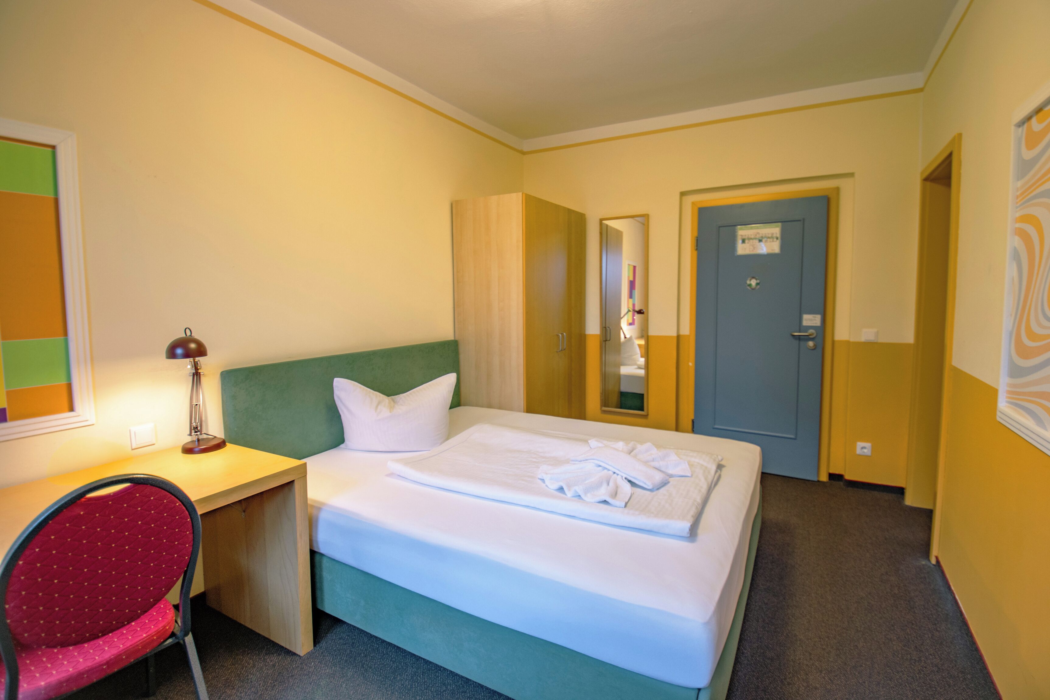 Una habitación de hotel con cama, escritorio, silla y puerta.
