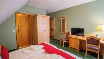 Habitación de hotel con cama, escritorio, silla, televisor y armario.
