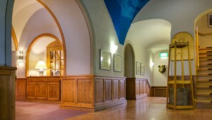 A spacious lobby with wooden paneling, a staircase, and a ceiling with a light projection. - Hotel Schloss Nebra (Nebra)