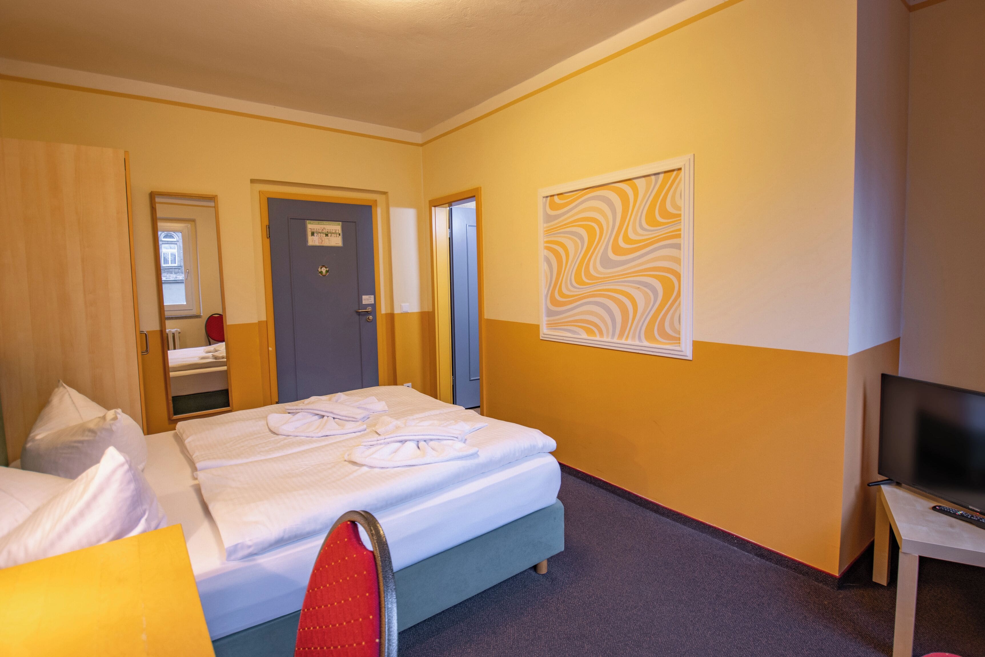 A hotel room with two beds, a TV, and a mirror.