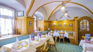 Un restaurante con interiores de madera, mesas dispuestas con manteles y servilletas blancas, y un suelo de diseño verde.