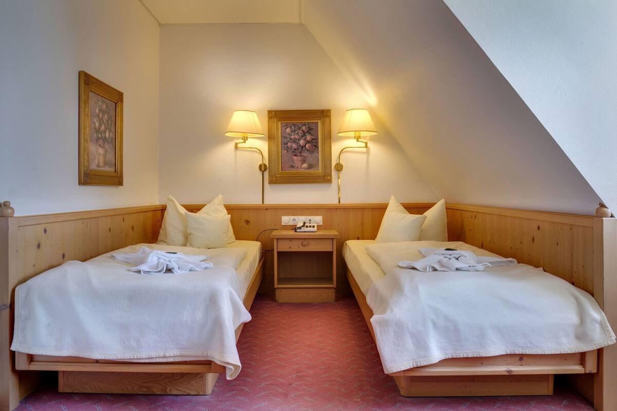 Ein Zimmer mit zwei Betten, einem Nachttisch und zwei Wandleuchten.