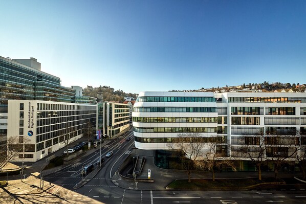 A modern building with a glass facade, multiple floors, and a parking lot with cars.