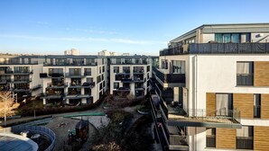 A modern apartment complex with multiple balconies, a central courtyard, and a view of the surrounding area.