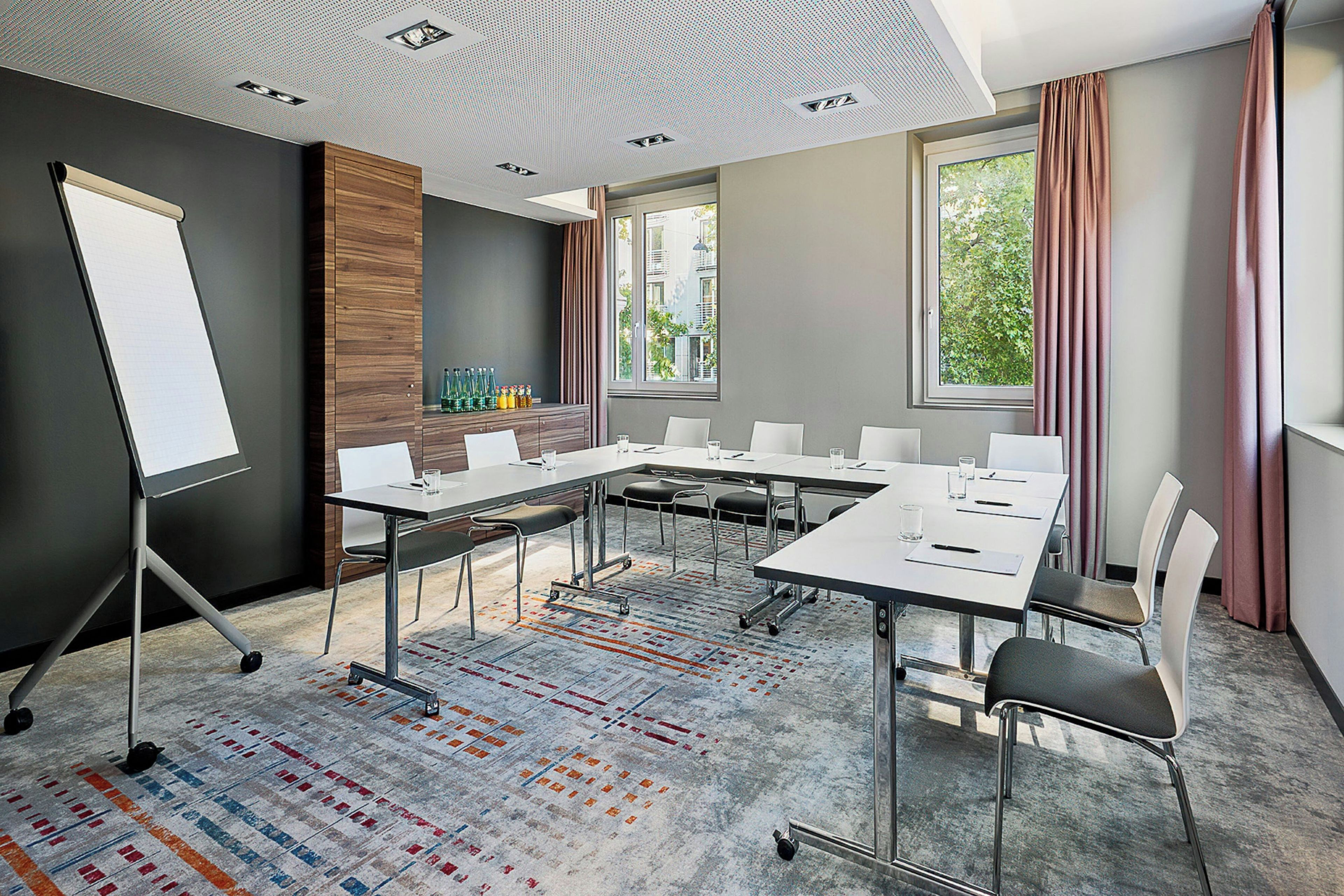 A conference room with a whiteboard, a long table with chairs, and a patterned carpet.