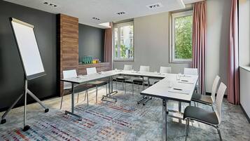 A conference room with a whiteboard, a long table with chairs, and a patterned carpet.