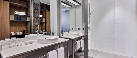 A modern bathroom with two sinks, a large mirror, and a glass shower enclosure.