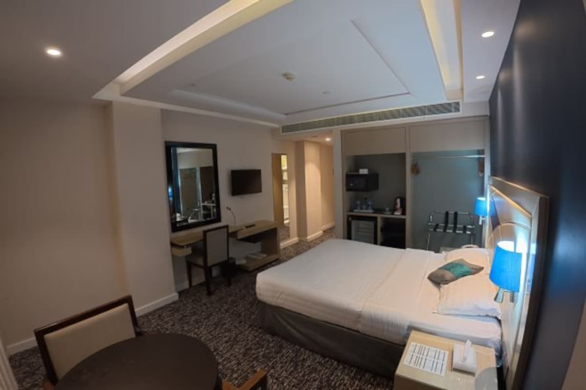 A hotel room with a bed, desk, chair, TV, and a mirror.