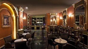 A bar area with tables and chairs, a bar counter, and shelves with bottles. - Al Sarab Hotel (Dubai)