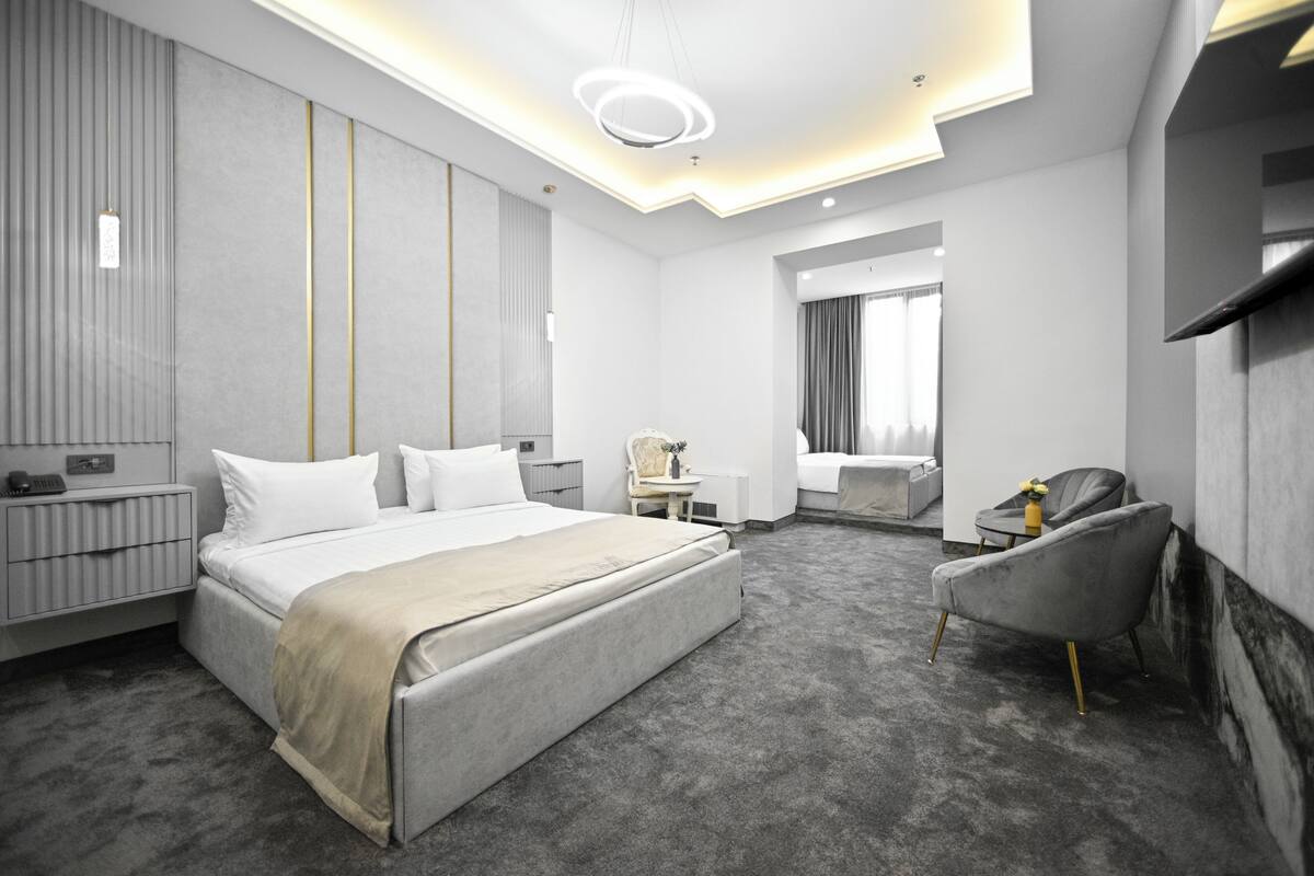 Ein modernes Hotelzimmer mit einem großen Bett, einem Schreibtisch, einem Sessel und einem Fernseher.