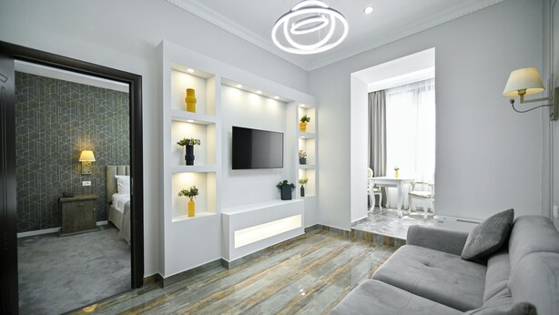 Een moderne woonkamer met een flatscreen televisie, inbouwplanken en een grijze bank.