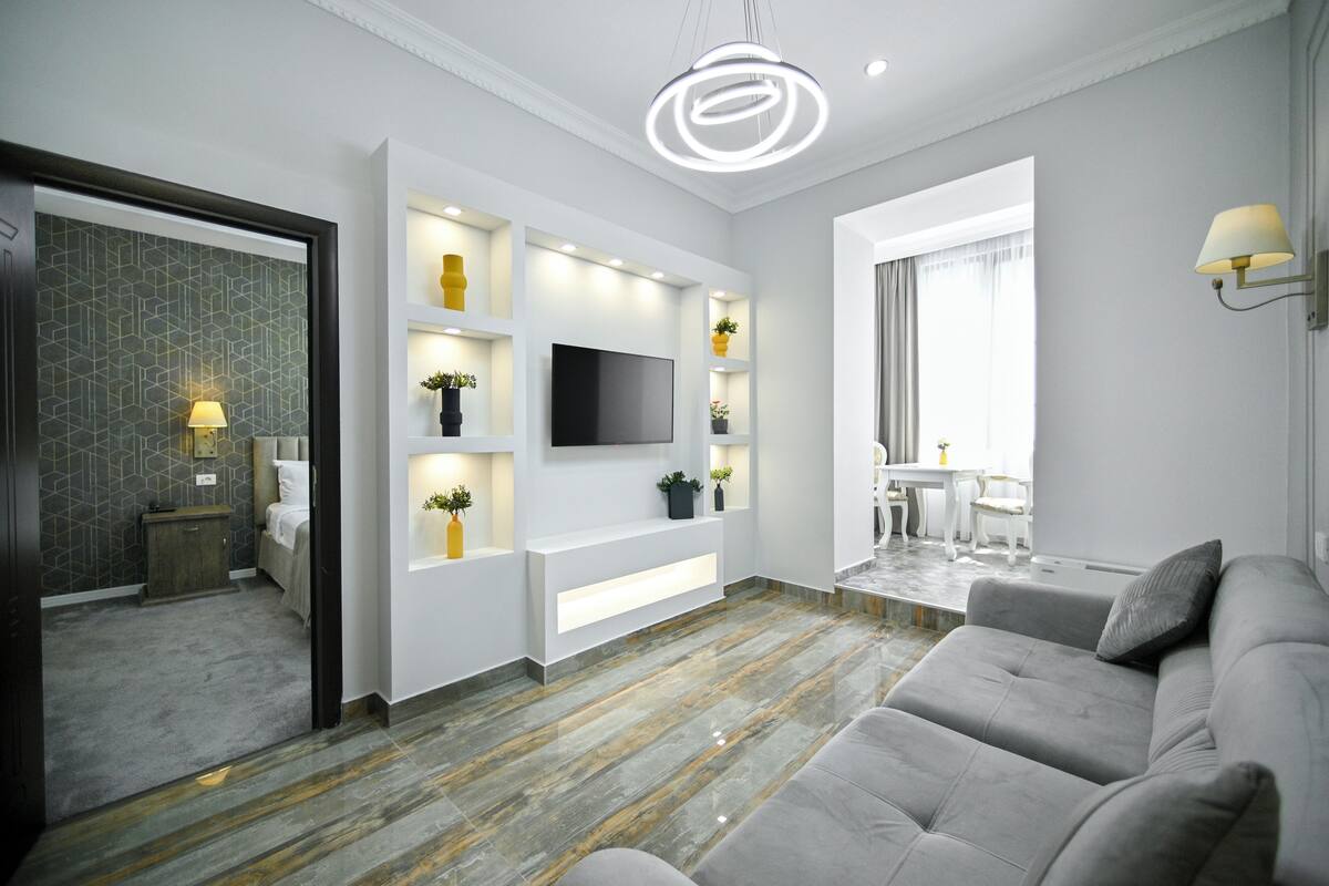 Ein modernes Wohnzimmer mit Flachbildfernseher, Einbauschränken und einem grauen Sofa.
