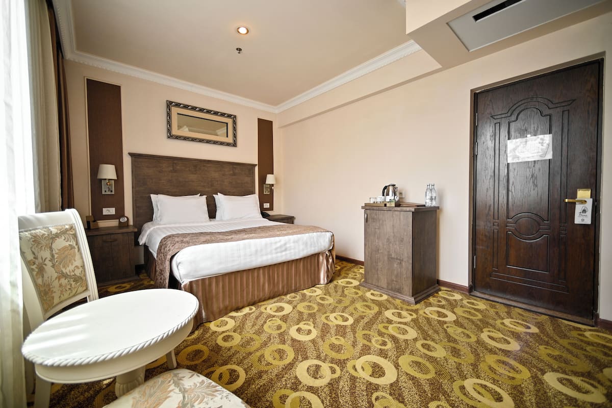 Ein Hotelzimmer mit Bett, Schreibtisch, Stuhl und Tür.