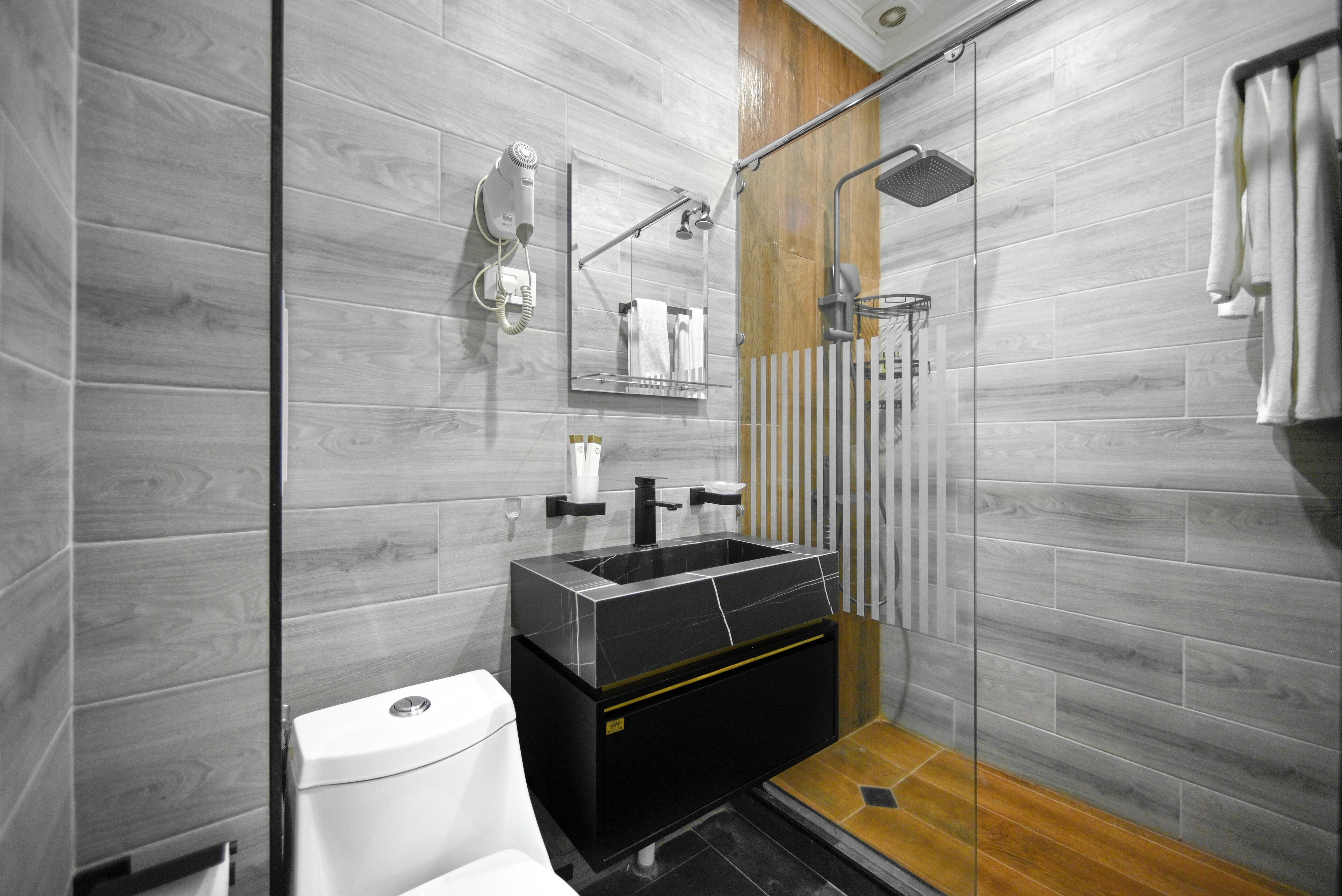 A modern bathroom with a glass shower enclosure, a black sink, and a white toilet.