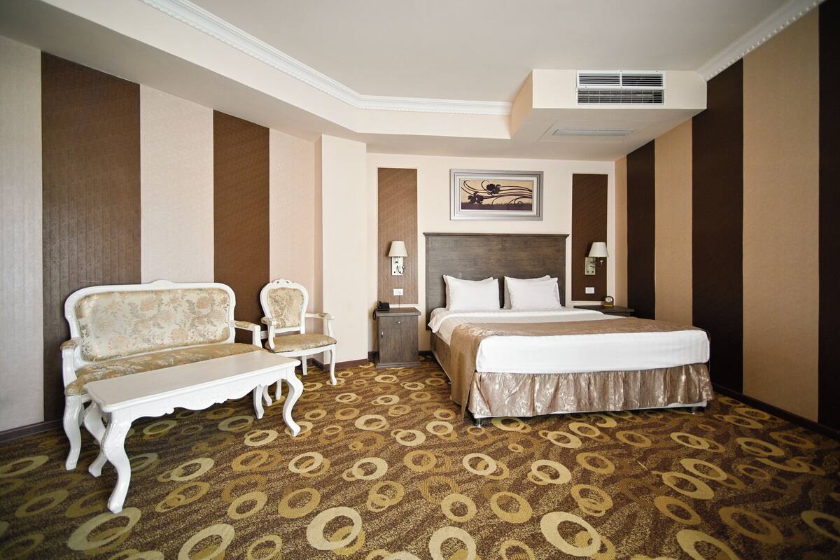Ein Hotelzimmer mit einem Bett, einem Sessel, einem kleinen Tisch und einem gemusterten Teppich.