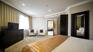 Een hotelkamer met een groot bed, een televisie, twee stoelen, een bureau en een kledingkast.