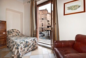 Une pièce comprenant un lit, un canapé en cuir et une fenêtre donnant sur un bâtiment à l’extérieur.