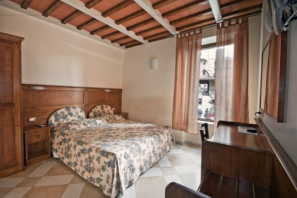 Ein Schlafzimmer mit Bett, Holz-Kopfteil, Nachttisch und Schreibtisch mit Stuhl.