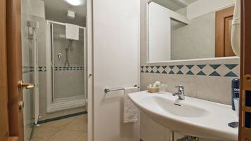 Une salle de bain avec une douche, un lavabo et un miroir.