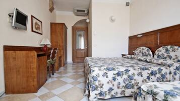 A bedroom with a bed, a desk, a chair, a television, and a door.