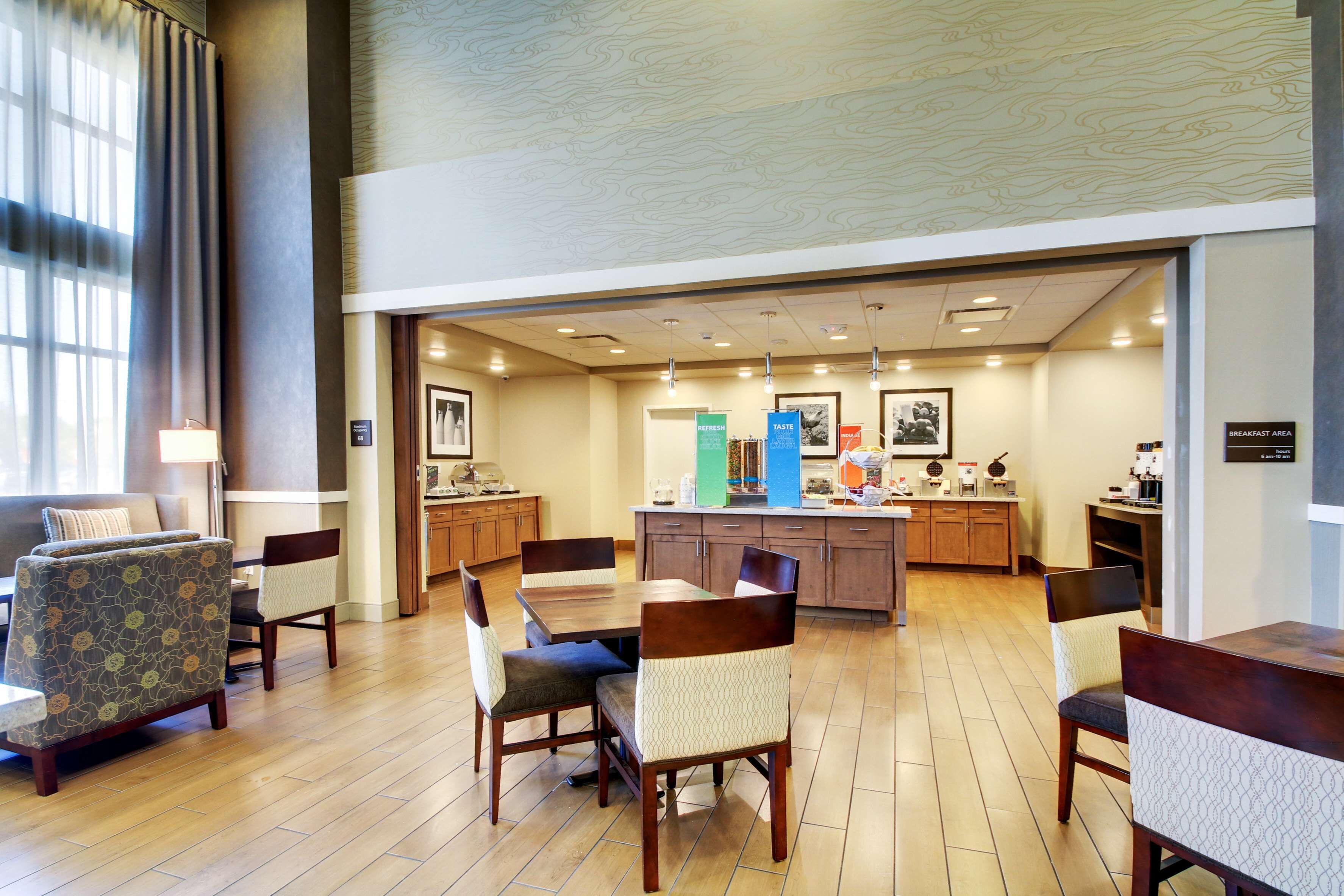 Un amplio vestíbulo de hotel con zona de comedor, cocina y barra de desayuno.