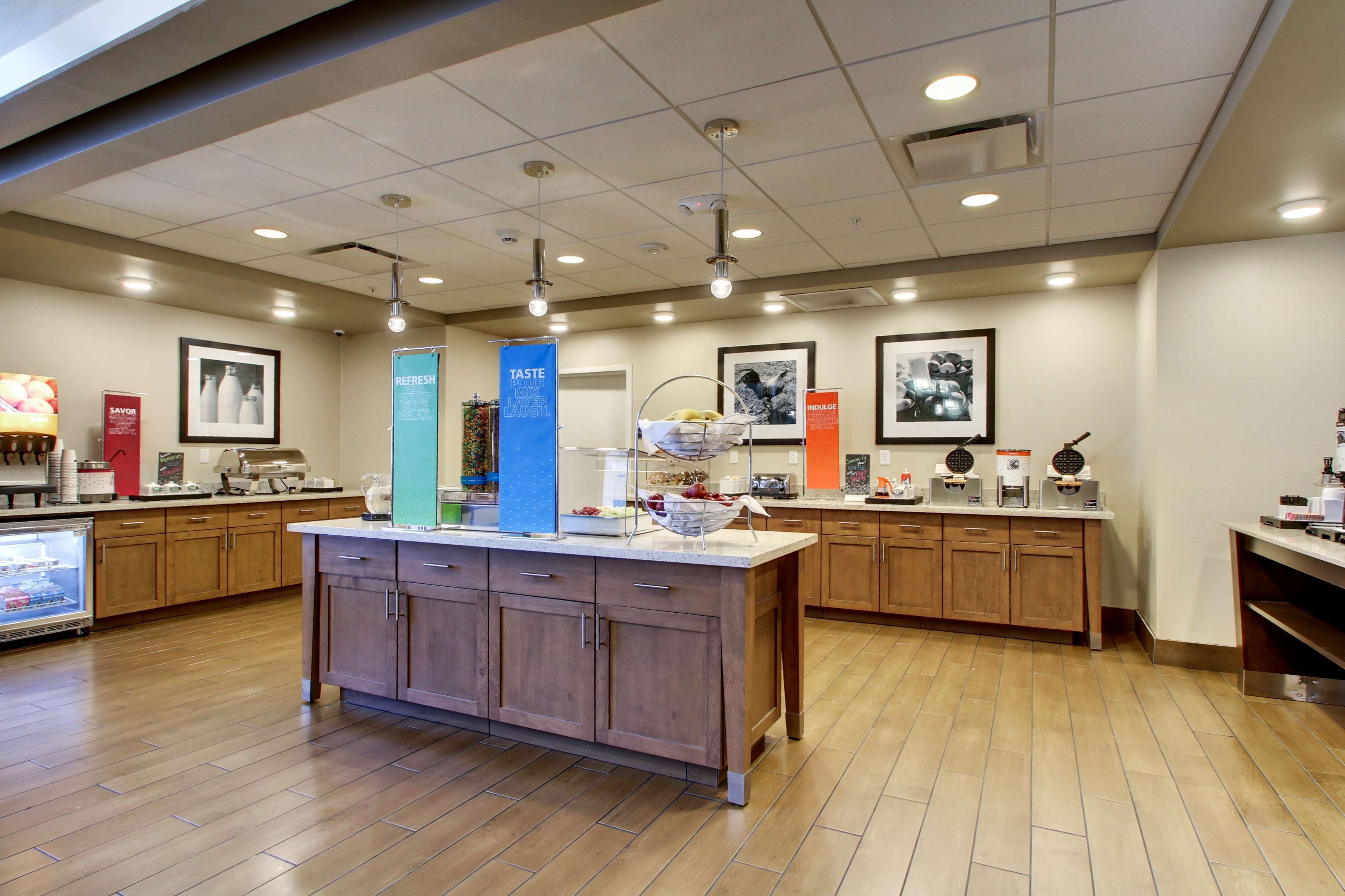 A modern kitchen with wooden cabinets, a central island, and various appliances.