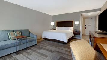 Una habitación de hotel con cama, sofá, escritorio y televisión.