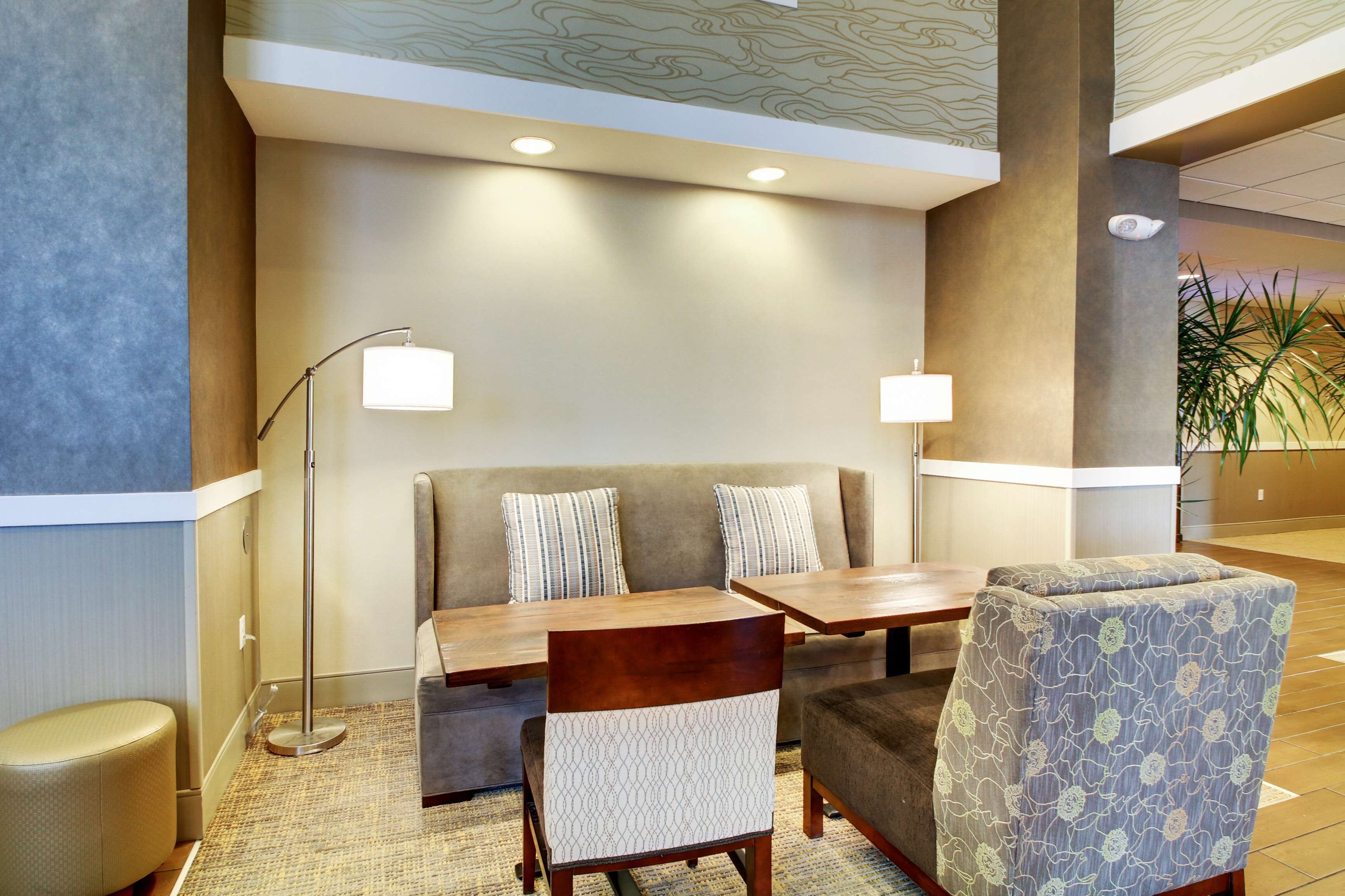 A lobby area with a sofa, two armchairs, a wooden table, and a floor lamp.