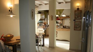 A kitchen with a dining area, featuring a wooden table, chairs, and a refrigerator. - La Terrazza di Reggello (Reggello)