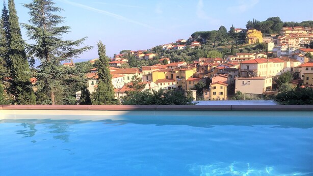 A swimming pool with a view of a hillside town. - La Terrazza di Reggello (Reggello)