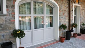 A stone building with a white arched door and potted plants. - La Terrazza di Reggello (Reggello)