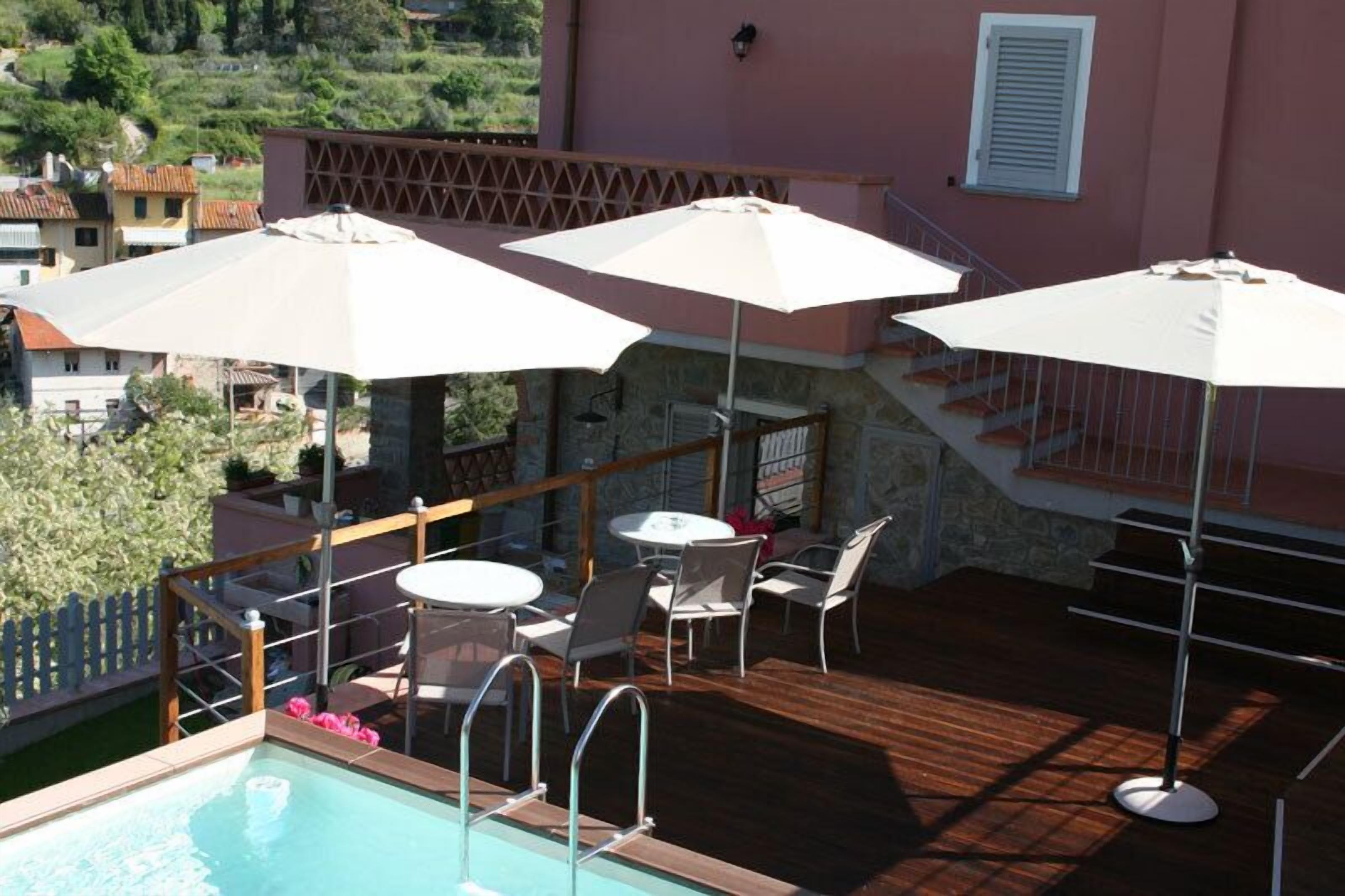 A rooftop terrace with a pool, outdoor seating, and umbrellas.