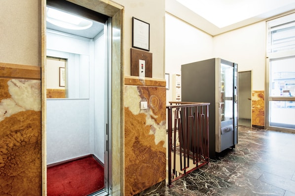 Un hall d’hôtel avec un sol en marbre, une moquette rouge et un comptoir d’accueil.