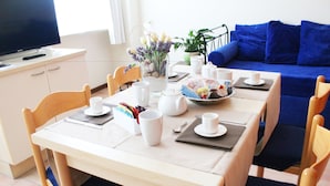 Una mesa de comedor dispuesta con vajilla blanca, un bol de aperitivos y una planta en maceta.