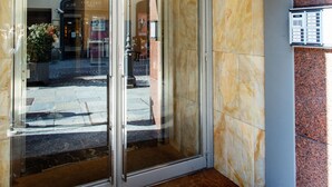 Entrada de hotel con puerta de vidrio y un cartel arriba.