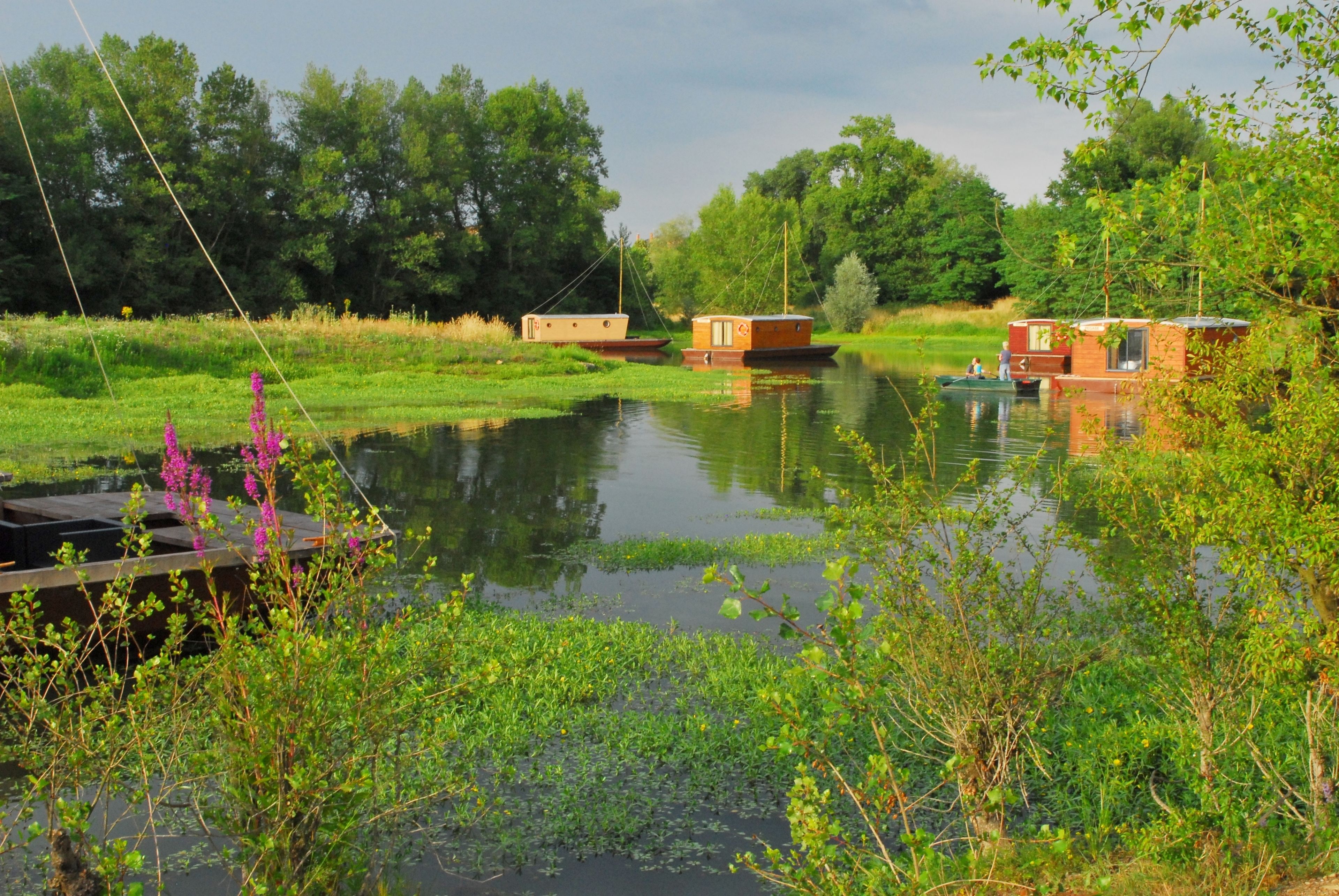 A calm river with boats and greenery.
