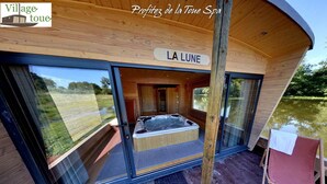 Une cabane en bois avec une porte en verre donnant sur une pièce où se trouve un jacuzzi.
