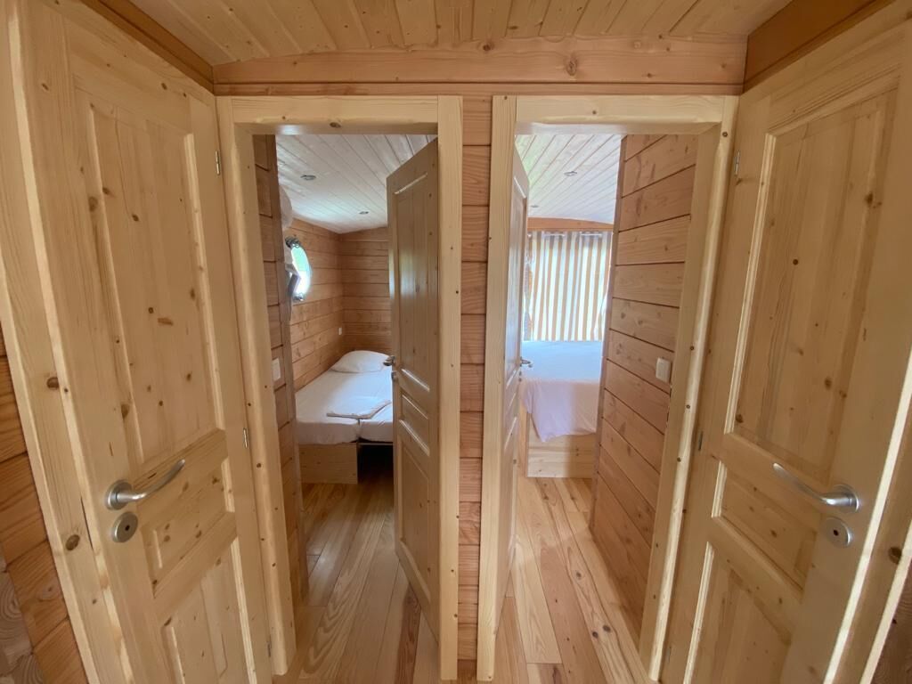 Une cabane en bois avec deux chambres, chacune comprenant un lit et une fenêtre.