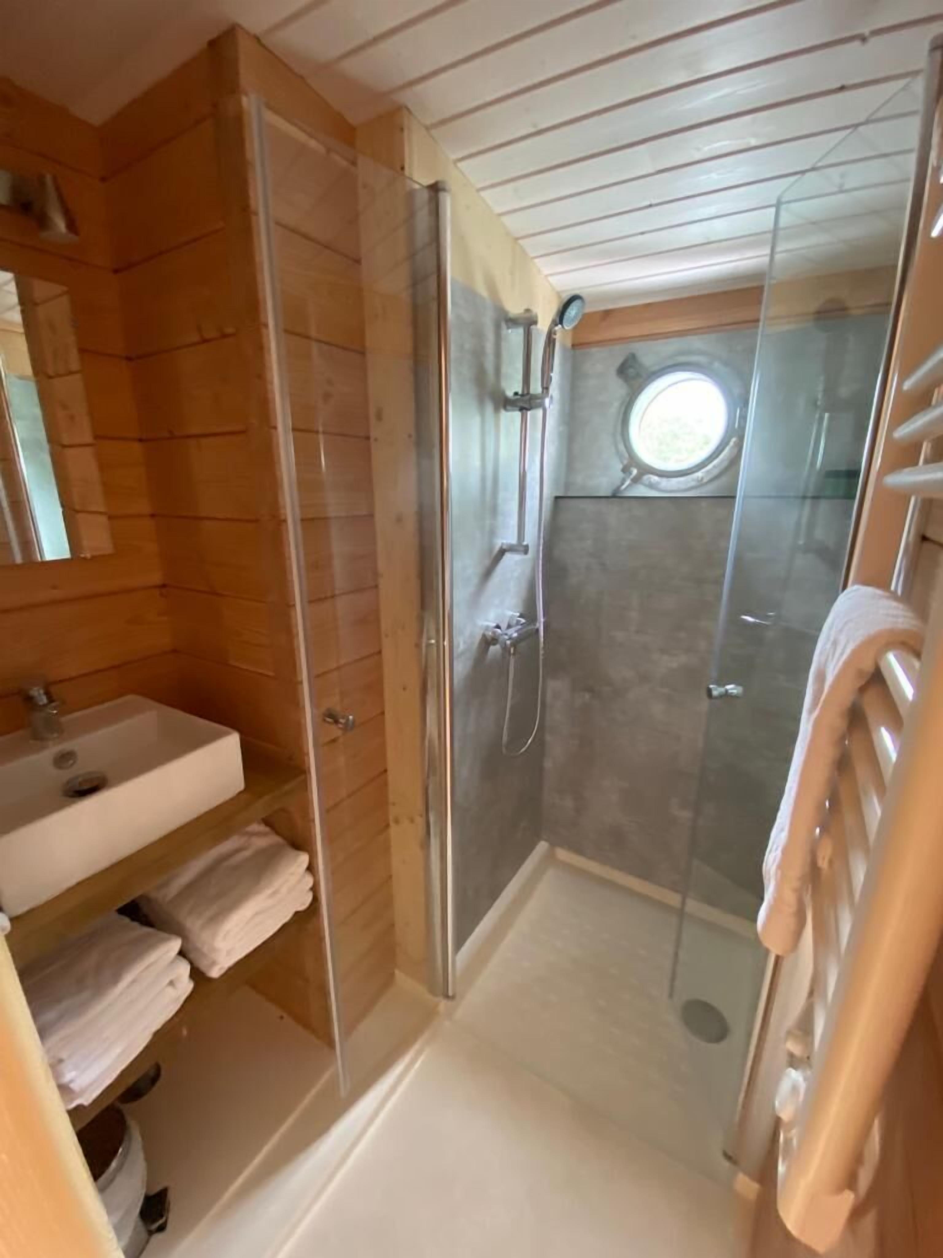 Une salle de bain compacte avec une douche à parois de verre, un lavabo et un porte-serviettes.
