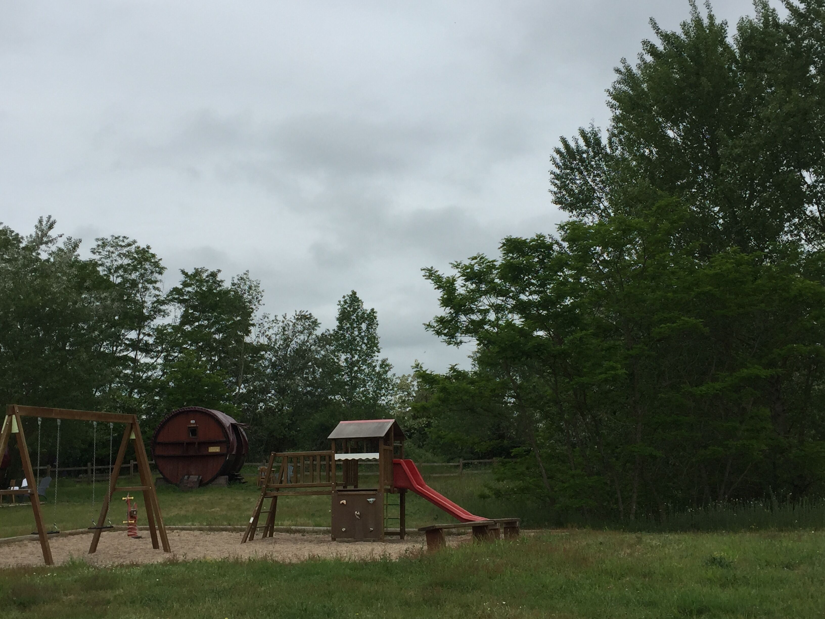 Une aire de jeux avec des balançoires, un toboggan et une structure d’escalade.